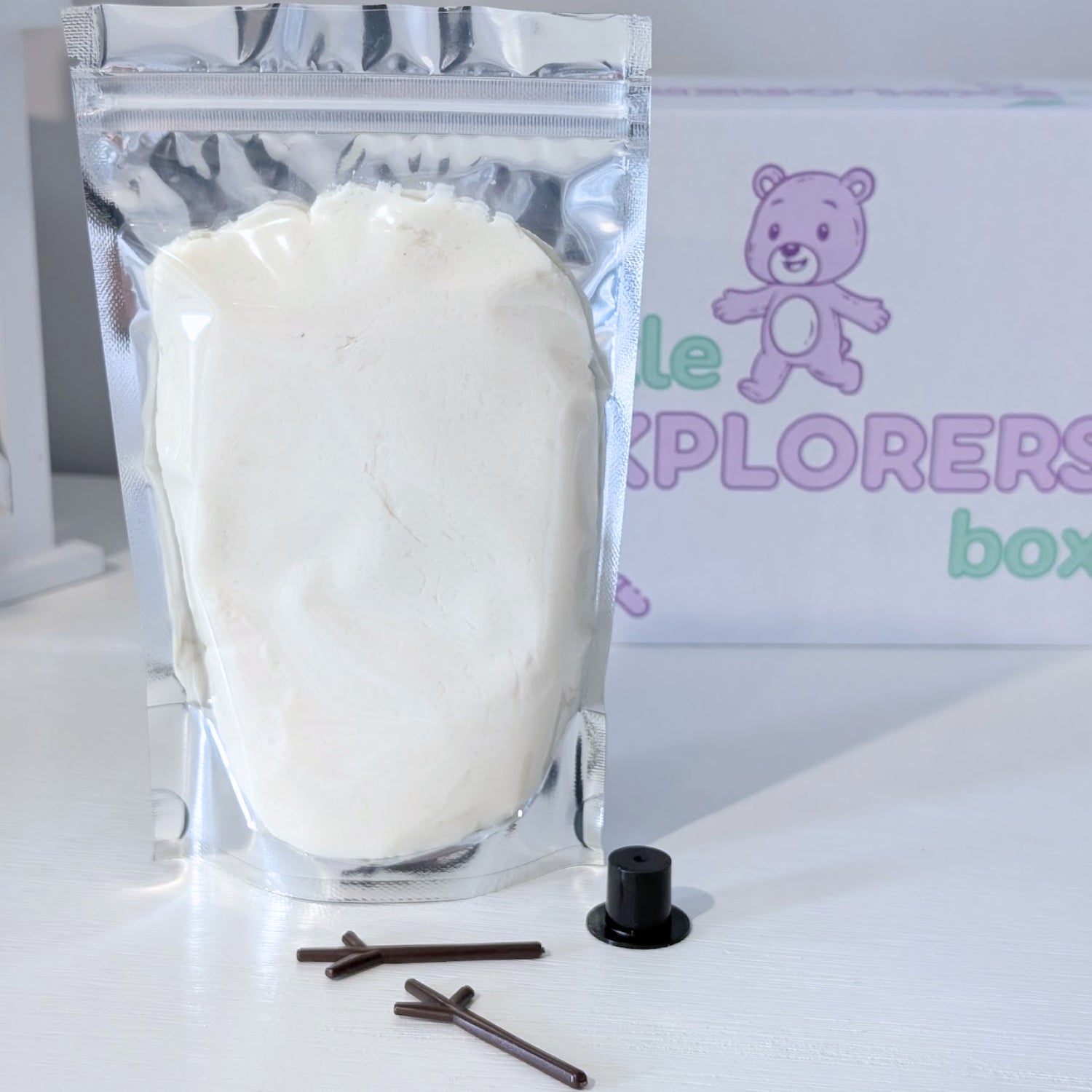 All the essentials to build your own frosty snow pal including snow white dough, hat and arms with 'Little Explorers' box in the background.