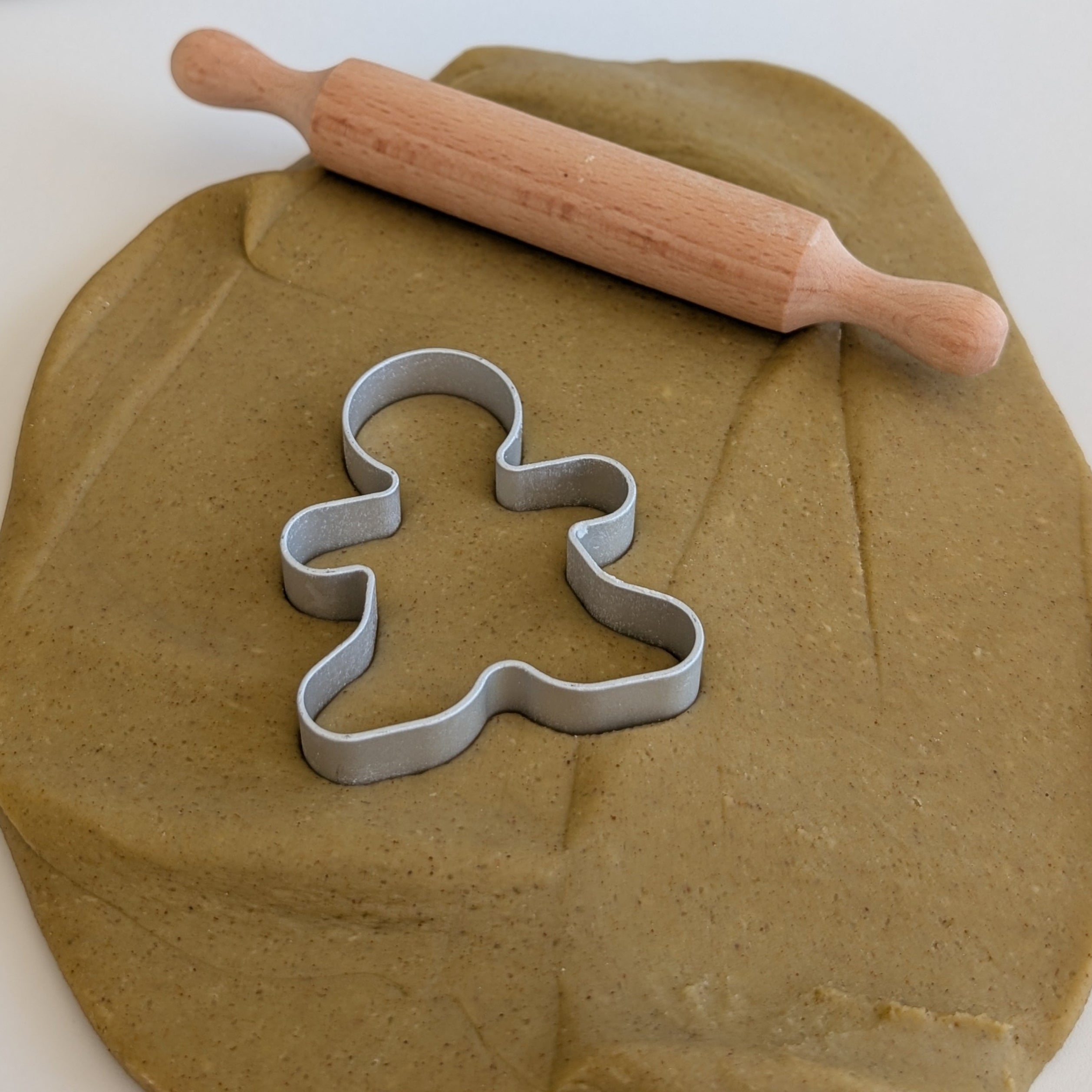 Play dough with a rolling pin and gingerbread man cutter on a white surface, with 'Little Explorers' box in the background.