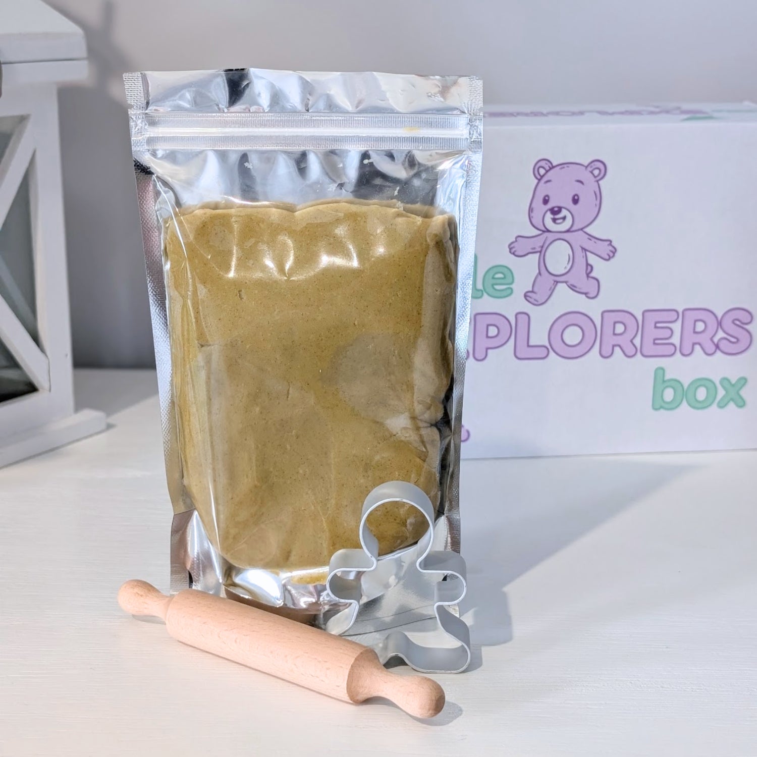 Ginger spiced packaged dough, rolling pin, and cookie cutter with 'Little Explorers Box' in the background
