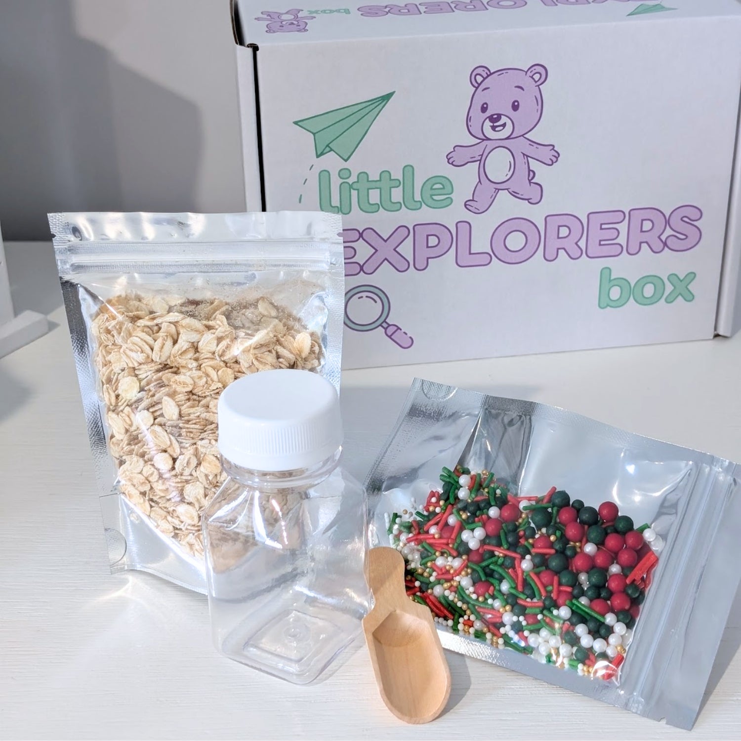 Make your own magical reindeer food kit with oats, small container, and colourful add ins next to a 'Little Explorers' box.