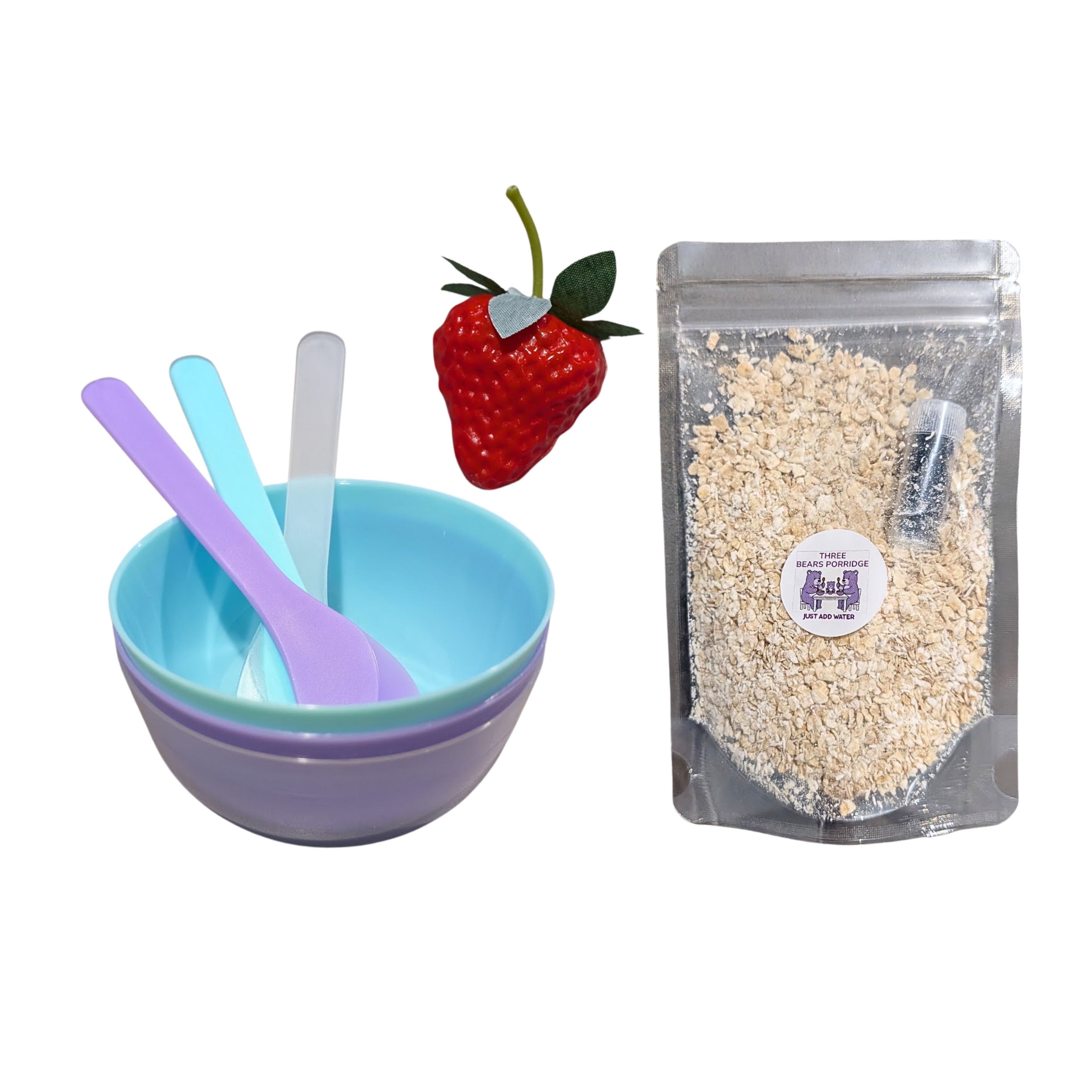 Set of bowls and spoons with a strawberry and a package of oats on a white background