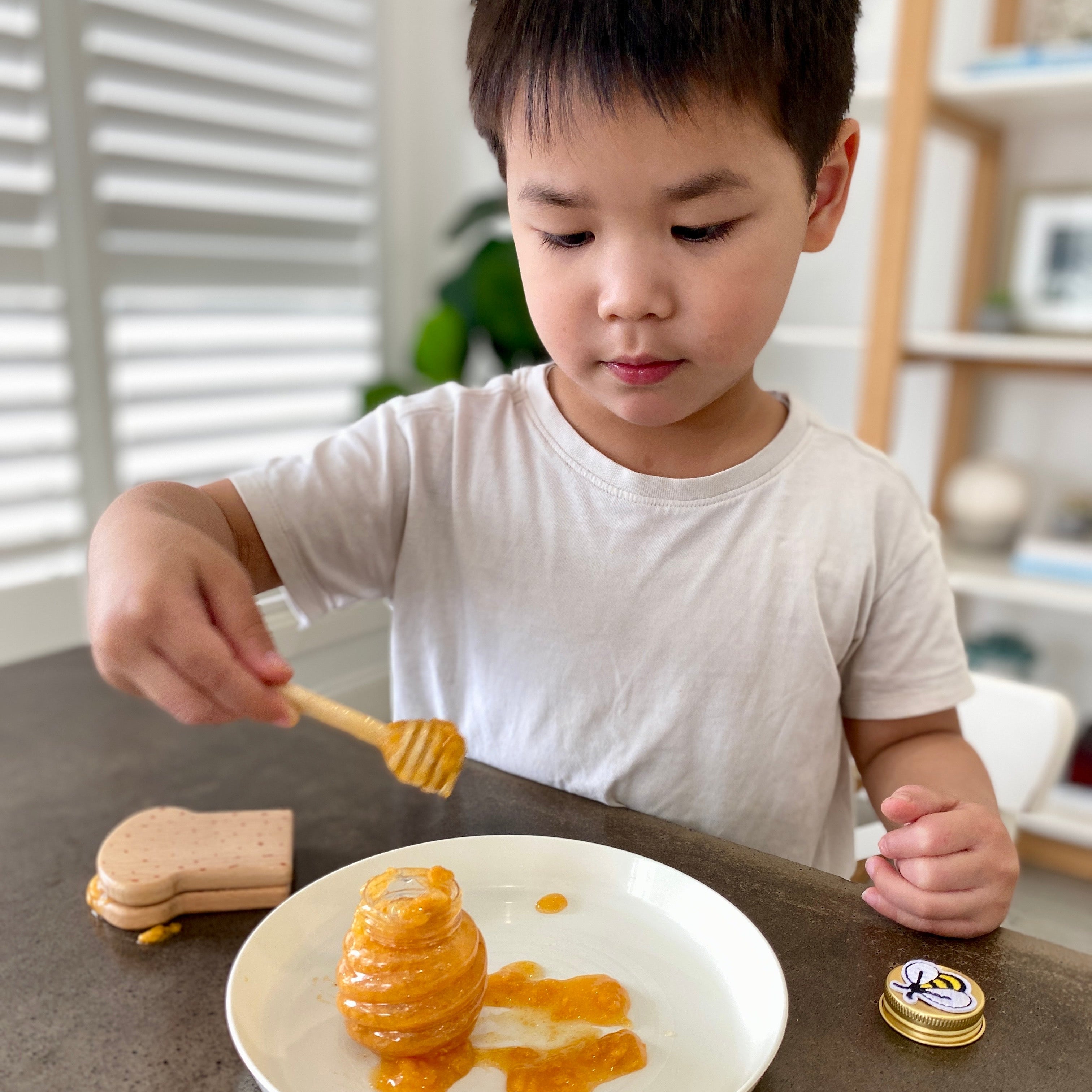 Child playing with honey on a plate in a kitchen setting