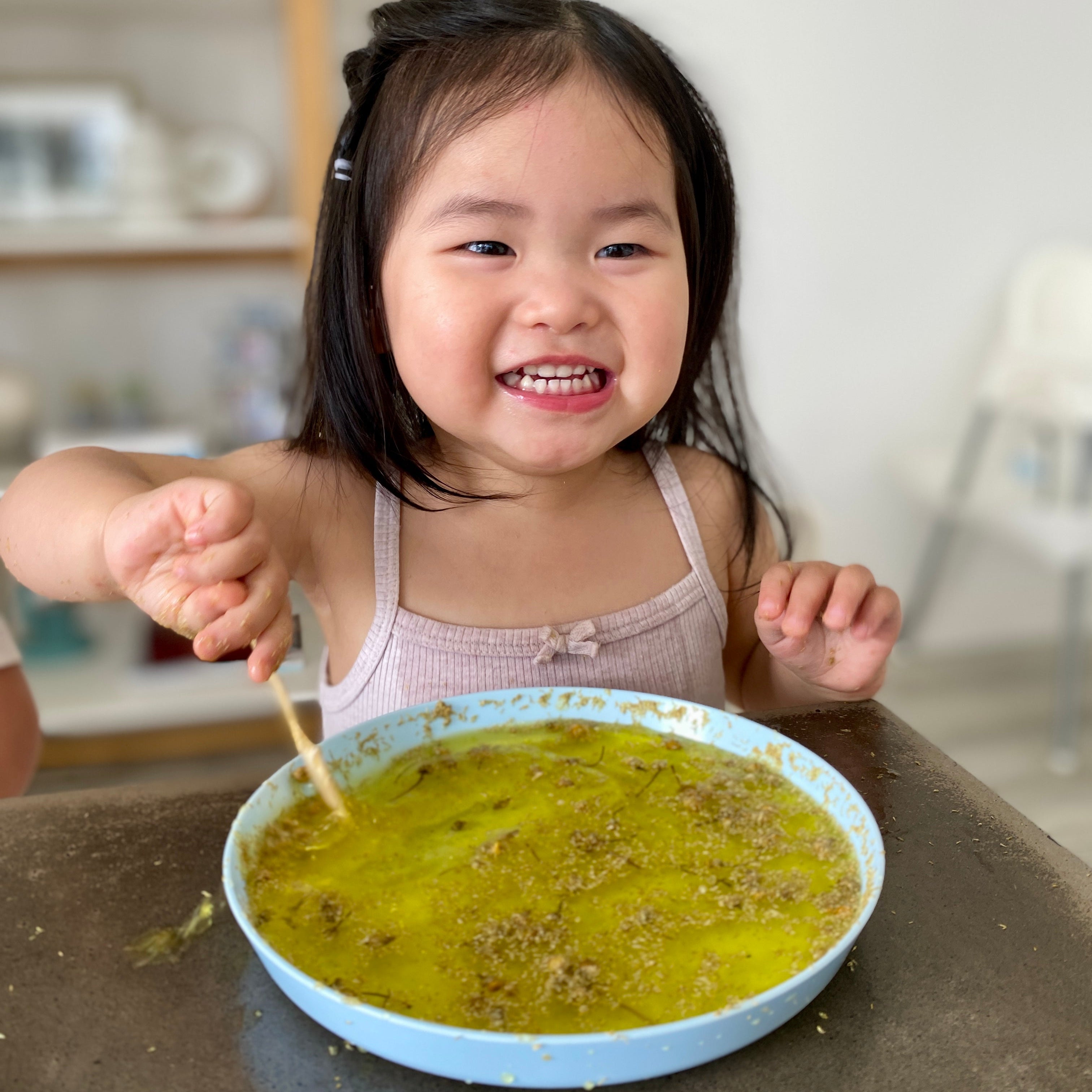 Child playing with a bowl of yellow shimmering flower potion